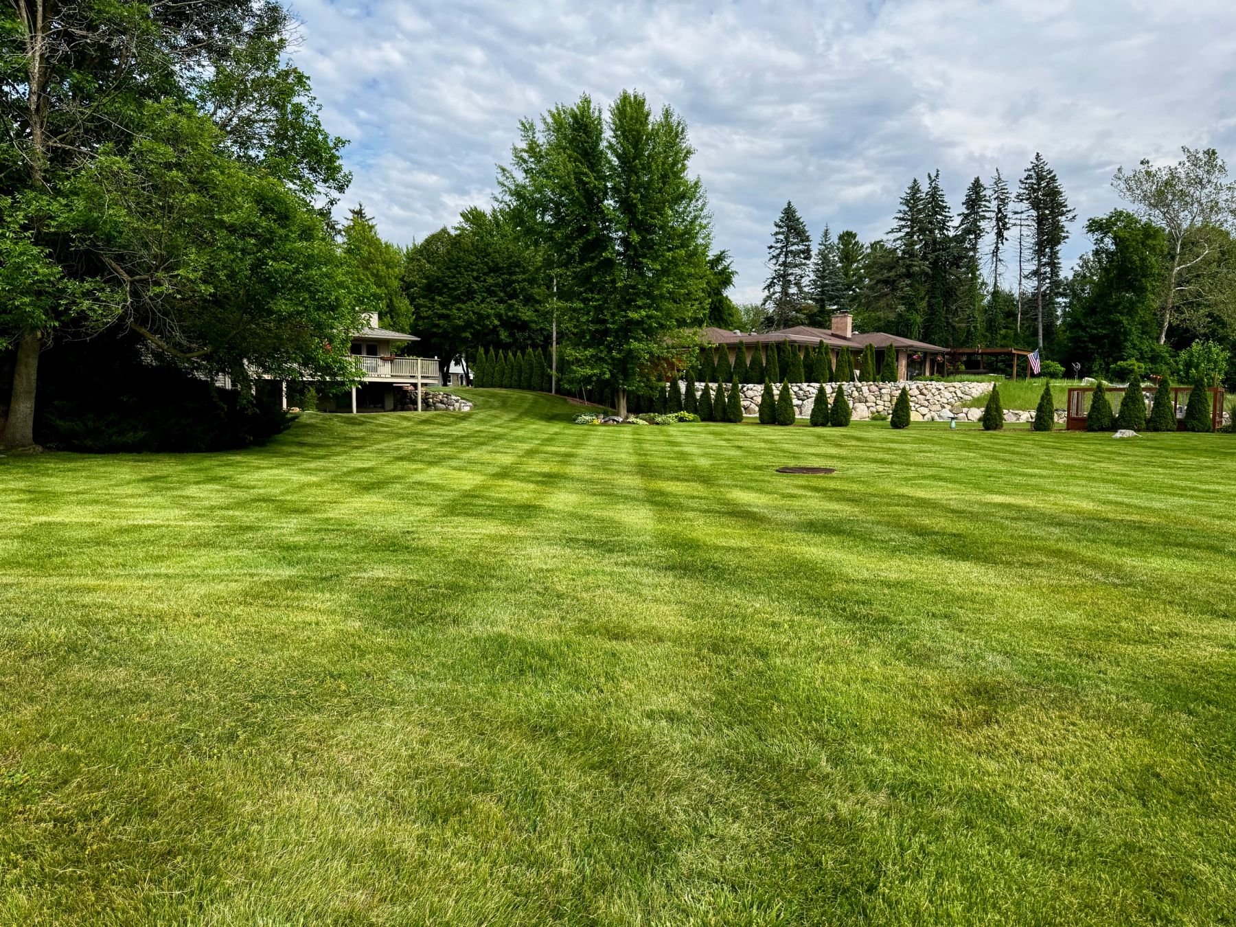 A striped lawn running back to planted beds and a covered patio
